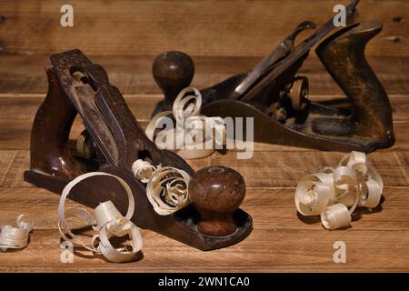 Alte Zimmermannsholzflugzeuge auf verbranntem Holz Hintergrund mit gebogenem Holz rasieren. Handwerkzeuge zur Holzbearbeitung Stockfoto