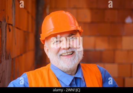 Lächelnder Bauarbeiter in Sicherheitsweste und Schutzhelm. Bärtiger Ingenieur, Architekt im Schutzhelm. Hausbau. Professionell Stockfoto