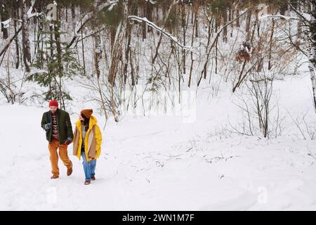 Extrem lange Aufnahme von jungen kaukasischen Männern und Frauen in der Liebe, die warme Kleidung tragen und am Wintertag wandern Stockfoto