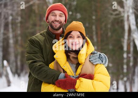 Mittleres Porträt eines glücklichen kaukasischen Mannes und einer verliebten Frau, die draußen stehen und am Wintertag in die Kamera lächeln Stockfoto