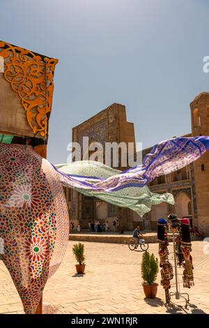 27. JUNI 2023, BUCHARA, USBEKISTAN: Schöne ethnische Stoffe, die mit dem Wind wehen, neben der alten Madrasah, Buchara, Usbekistan. Selektiver Fokus mit Stockfoto