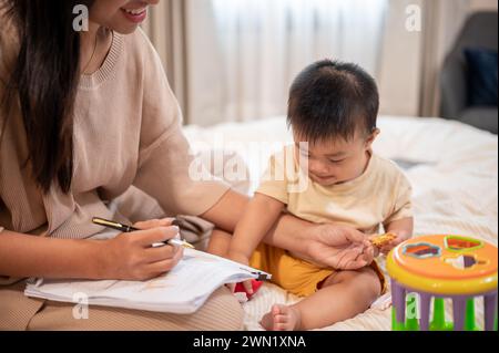 Ein süßer, unschuldiger asiatischer Junge versucht, seine Mutter zu spielen und zu stören, während sie zu Hause arbeitet. Kindheit, kleiner Sohn, Kind Stockfoto