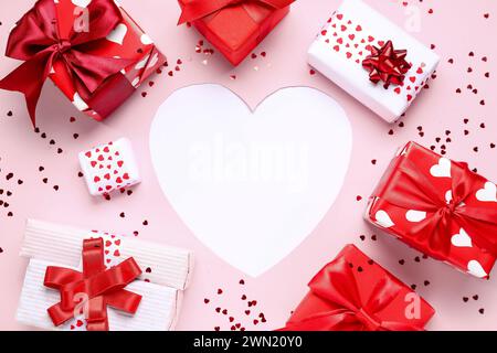 Herz aus Papier mit Geschenkschachteln und Konfetti auf rosa Hintergrund. Valentinstag-Feier Stockfoto