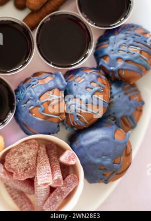 Eine Party-Platte für eine Kindergeburtstag mit bunten süßen Speisen wie Lollies, Süßigkeiten, Gelee und lila Plätzchen mit Schokoladenüberzug. Stockfoto