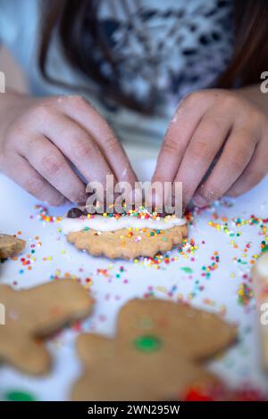 Kleine Hände dekorieren einen Weihnachtskeks mit Hunderten und Tausenden und festlichem Glück und Liebe. Stockfoto