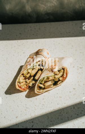 Blick von oben auf einen Burrito mit Eiern, Wurst, Käse und Tomaten auf einem Teller Stockfoto