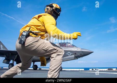 Pazifik. Februar 2024. Chief Aviation Boatswains Mate (Handling) Jeff Acevedo aus San Diego, der dem vorwärtsgerichteten amphibischen Angriffsträger USS America (LHA 6) zugeteilt wurde, signalisiert ein F-35B Lightning II Flugzeug vom 31st Marine Expeditionary Unit'ss (MEU) Air Combat Element (ACE), das während der Durchführung von Flugoperationen im Pazifik im Februar 18 startet. America, Leitschiff der America Amphibious Ready Group, ist im Einsatzgebiet der 7. US-Flotte im Einsatz. Die 7. US-Flotte ist die größte nach vorne ausgerichtete nummerierte Flotte der US-Navys und interagiert routinemäßig Stockfoto