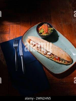 Hochwinkel eines Sandwiches mit grünem Blattgemüse, Gurkenscheiben und Kirschtomaten auf grünem Teller Stockfoto