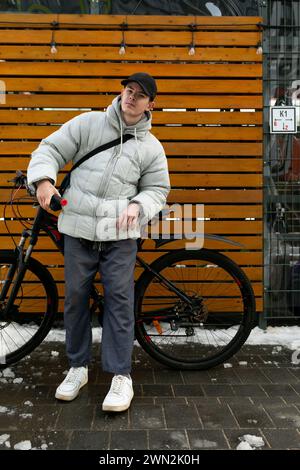 Fahrradverleih-Konzept. Ein Mann läuft im Winter mit dem Fahrrad durch die Stadt Stockfoto