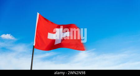 Schweizer Fahne winken gegen den blauen Himmel Stockfoto