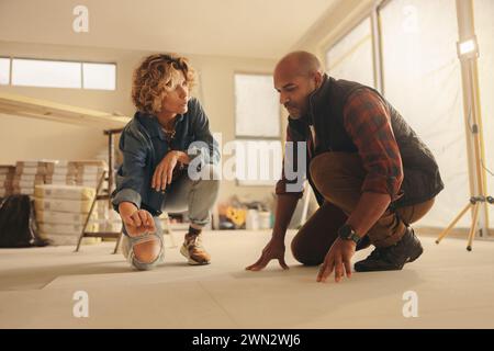 Mann und Frau diskutieren Hausrenovierung in ihrer Küche und arbeiten als Team zusammen. Sie planen einen Umbau, wobei der Schwerpunkt auf Bodenoptionen und Aufrüstungen liegt. Th Stockfoto