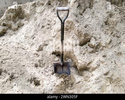 Eine Schaufel, die auf einer Baustelle im Sand steckt Stockfoto