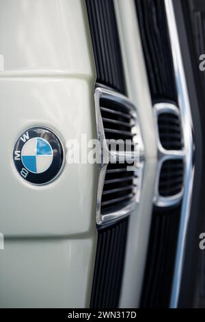 Rand der Motorhaube des alten hellgrünen BMW. Von oben auf den vorderen Teil des BMW der 1970er Jahre – Emblem und glänzender Stoßfänger aus Chrom. Stockfoto