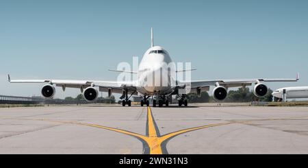 Riesige weiße Passagierflugzeuge, die an einem sonnigen Tag im Rollen sind, heiße Abgase aus dem Motor und verzerren die Sicht. Frontale symmetrische Ansicht. Stockfoto