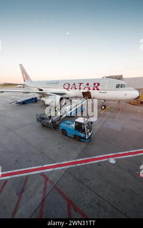 Qatar Airways Flugzeug auf der Jetbrücke nahe dem Teminal Gate. Qatar Airways – nationale Fluggesellschaft Katars. Gepäckbeladung und -Entladung vor dem Flug. Stockfoto