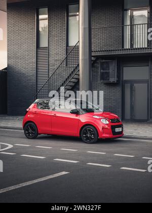Citroen C1 vor dem modernen Gebäude. Vorderansicht von drei Vierteln mit kompakter roter französischer Fließhecke in urbaner Umgebung - parkt auf der Straße in der Innenstadt Stockfoto