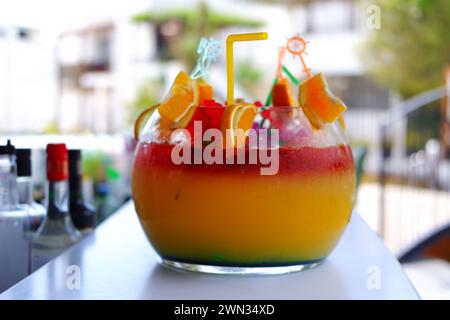 Großes kugelförmiges Glas für Kokzidiosen im Freien auf dem Bartisch im Sommer. Bokeh mit Stühlen im Hintergrund. Stockfoto