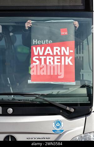 29. Februar 2024, Sachsen-Anhalt, Halle (Saale): Ein Mitarbeiter der Hallesche Verkehrs-AG (HAVAG) bringt während eines Warnstreiks auf einem Bus an einem Depot ein Warnstreikplakat an. Die gewerkschaft Verdi hatte in mehreren bundesländern Beschäftigte des öffentlichen Verkehrs aufgefordert, im bundesweiten Lohnstreit in regionalen Verhandlungen einen Warnstreik zu führen. Foto: Jan Woitas/dpa Stockfoto