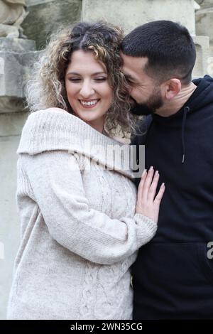 Ein Paar, das vor einer Statue kuschelt und lächelt Stockfoto