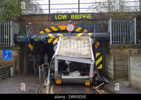 Slough, Berkshire, Großbritannien. Februar 2024. Ein Van ist in der Station Road in Slough nahe der Burnham Station auf die Eisenbahnbrücke gestoßen. Die Niederbrücke, die deutlich als Niederbrücke gekennzeichnet ist und ein blinkendes Schild zur Warnung von Fahrzeugen hat, liegt unterhalb der Eisenbahnlinie, die von Elizabeth Line und GWR-Zügen genutzt wird. Die Züge fahren jedoch noch. Das Fahrerhaus wurde weggefahren und der Inhalt, der wie Baumüll aussieht, wurde verstreut in der Brücke zurückgelassen. Der Van hat ein Logo für Lambournes, 24-Stunden-Hecklift und Shutter-Reparaturen auf der Rückseite. Die Straße ist Stockfoto