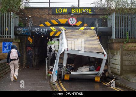 Slough, Berkshire, Großbritannien. Februar 2024. Ein Van ist in der Station Road in Slough nahe der Burnham Station auf die Eisenbahnbrücke gestoßen. Die Niederbrücke, die deutlich als Niederbrücke gekennzeichnet ist und ein blinkendes Schild zur Warnung von Fahrzeugen hat, liegt unterhalb der Eisenbahnlinie, die von Elizabeth Line und GWR-Zügen genutzt wird. Die Züge fahren jedoch noch. Das Fahrerhaus wurde weggefahren und der Inhalt, der wie Baumüll aussieht, wurde verstreut in der Brücke zurückgelassen. Der Van hat ein Logo für Lambournes, 24-Stunden-Hecklift und Shutter-Reparaturen auf der Rückseite. Die Straße ist Stockfoto