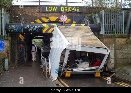 Slough, Berkshire, Großbritannien. Februar 2024. Ein Van ist in der Station Road in Slough nahe der Burnham Station auf die Eisenbahnbrücke gestoßen. Die Niederbrücke, die deutlich als Niederbrücke gekennzeichnet ist und ein blinkendes Schild zur Warnung von Fahrzeugen hat, liegt unterhalb der Eisenbahnlinie, die von Elizabeth Line und GWR-Zügen genutzt wird. Die Züge fahren jedoch noch. Das Fahrerhaus wurde weggefahren und der Inhalt, der wie Baumüll aussieht, wurde verstreut in der Brücke zurückgelassen. Der Van hat ein Logo für Lambournes, 24-Stunden-Hecklift und Shutter-Reparaturen auf der Rückseite. Die Straße ist Stockfoto