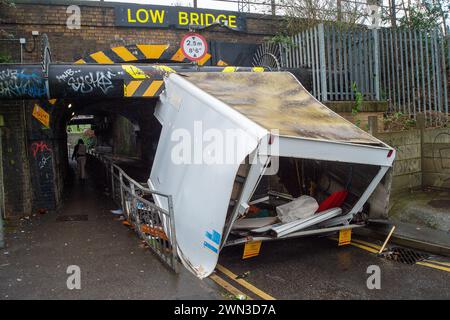 Slough, Berkshire, Großbritannien. Februar 2024. Ein Van ist in der Station Road in Slough nahe der Burnham Station auf die Eisenbahnbrücke gestoßen. Die Niederbrücke, die deutlich als Niederbrücke gekennzeichnet ist und ein blinkendes Schild zur Warnung von Fahrzeugen hat, liegt unterhalb der Eisenbahnlinie, die von Elizabeth Line und GWR-Zügen genutzt wird. Die Züge fahren jedoch noch. Das Fahrerhaus wurde weggefahren und der Inhalt, der wie Baumüll aussieht, wurde verstreut in der Brücke zurückgelassen. Der Van hat ein Logo für Lambournes, 24-Stunden-Hecklift und Shutter-Reparaturen auf der Rückseite. Die Straße ist Stockfoto