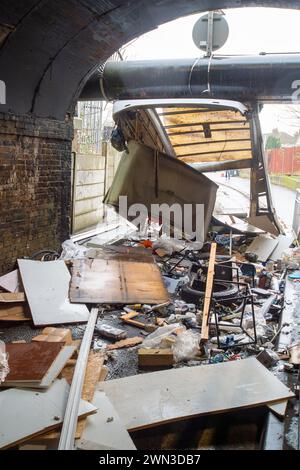 Slough, Berkshire, Großbritannien. Februar 2024. Ein Van ist in der Station Road in Slough nahe der Burnham Station auf die Eisenbahnbrücke gestoßen. Die Niederbrücke, die deutlich als Niederbrücke gekennzeichnet ist und ein blinkendes Schild zur Warnung von Fahrzeugen hat, liegt unterhalb der Eisenbahnlinie, die von Elizabeth Line und GWR-Zügen genutzt wird. Die Züge fahren jedoch noch. Das Fahrerhaus wurde weggefahren und der Inhalt, der wie Baumüll aussieht, wurde verstreut in der Brücke zurückgelassen. Der Van hat ein Logo für Lambournes, 24-Stunden-Hecklift und Shutter-Reparaturen auf der Rückseite. Die Straße ist Stockfoto