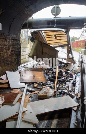 Slough, Berkshire, Großbritannien. Februar 2024. Ein Van ist in der Station Road in Slough nahe der Burnham Station auf die Eisenbahnbrücke gestoßen. Die Niederbrücke, die deutlich als Niederbrücke gekennzeichnet ist und ein blinkendes Schild zur Warnung von Fahrzeugen hat, liegt unterhalb der Eisenbahnlinie, die von Elizabeth Line und GWR-Zügen genutzt wird. Die Züge fahren jedoch noch. Das Fahrerhaus wurde weggefahren und der Inhalt, der wie Baumüll aussieht, wurde verstreut in der Brücke zurückgelassen. Der Van hat ein Logo für Lambournes, 24-Stunden-Hecklift und Shutter-Reparaturen auf der Rückseite. Die Straße ist Stockfoto