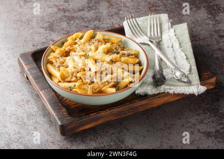 Cremige Pasta im Stil französischer Zwiebeln mit karamelisierten Zwiebeln, Thymian, Knoblauch und Greyerkäse in Nahaufnahme auf einer Schüssel auf einem Holzbrett. Horizontal Stockfoto