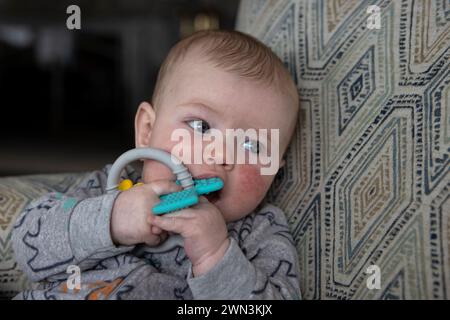 4 Monate alter Junge, der ein Spielzeug im Mund hält. Stockfoto