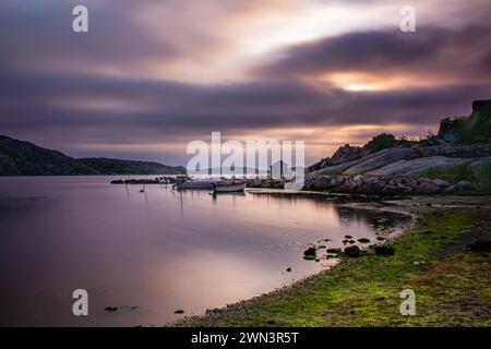 Der Sonnenuntergang über dem ruhigen Fluss mit verankerten Booten in der Abenddämmerung Stockfoto