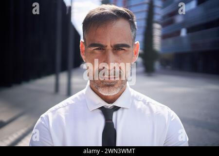 Nahaufnahme eines reiferen Geschäftsmannes mit selbstbewusstem Blick auf die Kamera, die außerhalb des Gebäudes steht. Stockfoto