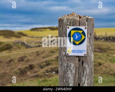 Anglesey, Vereinigtes Königreich - 11. Januar 2024: Ein verwittertes hölzernes Schild, das den Weg für Wanderer auf dem Wales Coast Path auf der Insel Anglesey in Nordwales zeigt Stockfoto