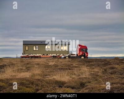 Anglesey, Vereinigtes Königreich - 11. Januar 2024: Ein Sattelzugwagen bringt eine Ferienwohnung zu einem Campingplatz in Anglesey, Nordwales, Vereinigtes Königreich. An einem teilweise sonnigen Tag Stockfoto