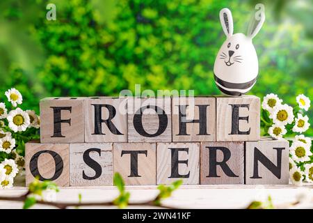 Augsburg, Bayern, Deutschland - 28. Februar 2024: Happy Easter geschrieben mit Holzwürfeln, Osterhasen-Ei und Frühlingsblumen. Ostersymbolbild *** Frohe Ostern schreibt mit Holzwürfeln, Osterhasen EI und frühlings Blumen. Oster-Symbolbild Stockfoto