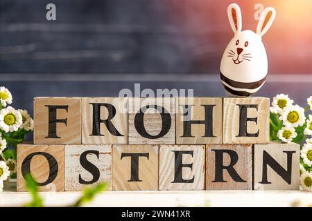 Augsburg, Bayern, Deutschland - 28. Februar 2024: Happy Easter geschrieben mit Holzwürfeln, Osterhasen-Ei und Frühlingsblumen. Ostersymbolbild *** Frohe Ostern schreibt mit Holzwürfeln, Osterhasen EI und frühlings Blumen. Oster-Symbolbild Stockfoto