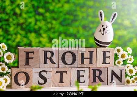 Augsburg, Bayern, Deutschland - 28. Februar 2024: Happy Easter geschrieben mit Holzwürfeln, Osterhasen-Ei und Frühlingsblumen. Ostersymbolbild *** Frohe Ostern schreibt mit Holzwürfeln, Osterhasen EI und frühlings Blumen. Oster-Symbolbild Stockfoto