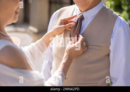 Die ältere Frau passt die Krawatte ihres Mannes an Stockfoto