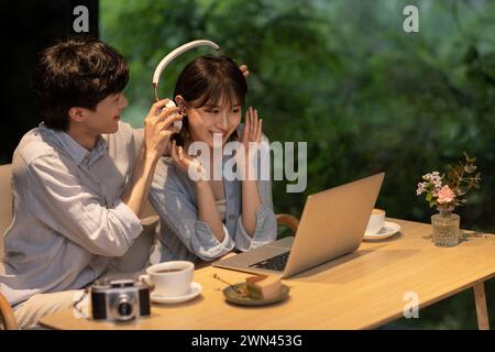 Ein junges Paar, das im Café einen Laptop benutzt Stockfoto