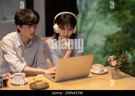 Ein junges Paar, das im Café einen Laptop benutzt Stockfoto