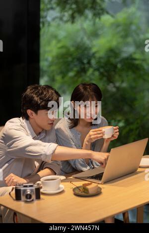Ein junges Paar, das im Café einen Laptop benutzt Stockfoto