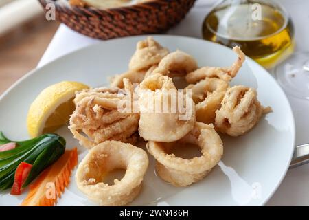 Nahaufnahme von gebratenem Tintenfisch in Teig, serviert auf einem weißen Teller in einem mediterranen Restaurant. Meeresfrüchte als Teil der mediterranen Küche Stockfoto
