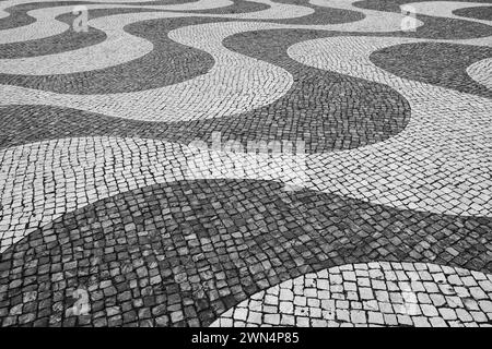 Typisch portugiesisches Mosaik-Pflastersteinpflaster in Lissabon, Portugal, schwarz-weiß. Stockfoto