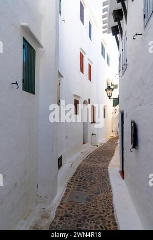 Binibeca Vell, Spanien - 24. Januar 2024: Enge Gasse führt durch ein Labyrinth von weiß getünchten Gebäuden im Dorfzentrum von Binibeca Vell Stockfoto