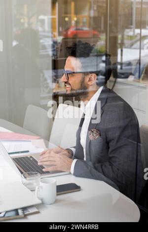 Seitenansicht eines männlichen Immobilienmaklers mit Laptop im Büro Stockfoto