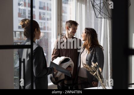 Glückliches multirassisches Paar mit Verkäuferin in einem neuen Zuhause Stockfoto