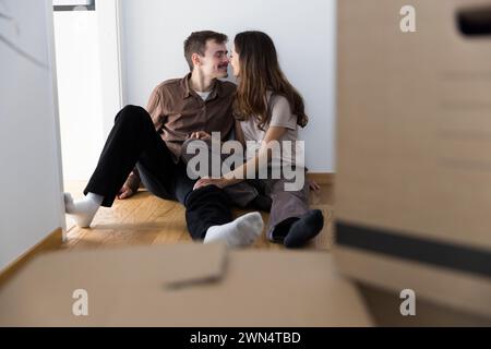 Liebevolles multirassisches Paar, das sich gegenseitig küsst, während er zu Hause sitzt Stockfoto
