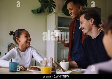 Glückliches Schwulenpaar mit Tochter, die frühstücken, während sie zu Hause am Esstisch saßen Stockfoto