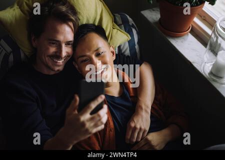 Hochwinkelansicht eines multirassischen Schwulen-Paares mit Smartphone zu Hause Stockfoto